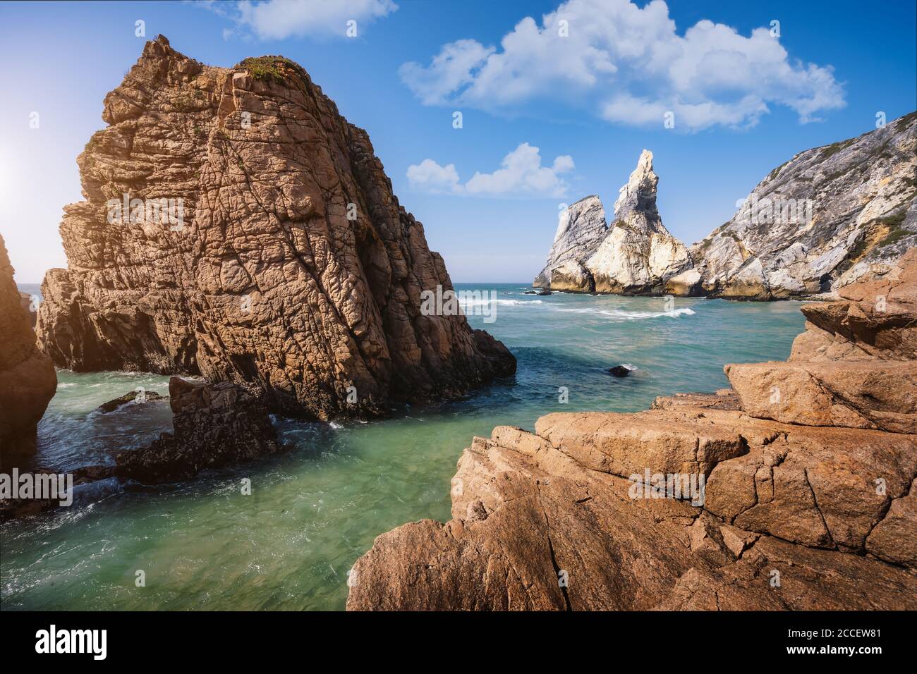 Strand von Ursa, Sintra, Portugal. Epische Seenlandschaft mit Klippen, die sich vom smaragdgrünen atlantik emporragen. Weiße Wolken am blauen Himmel. Sommerurlaub Stockfoto