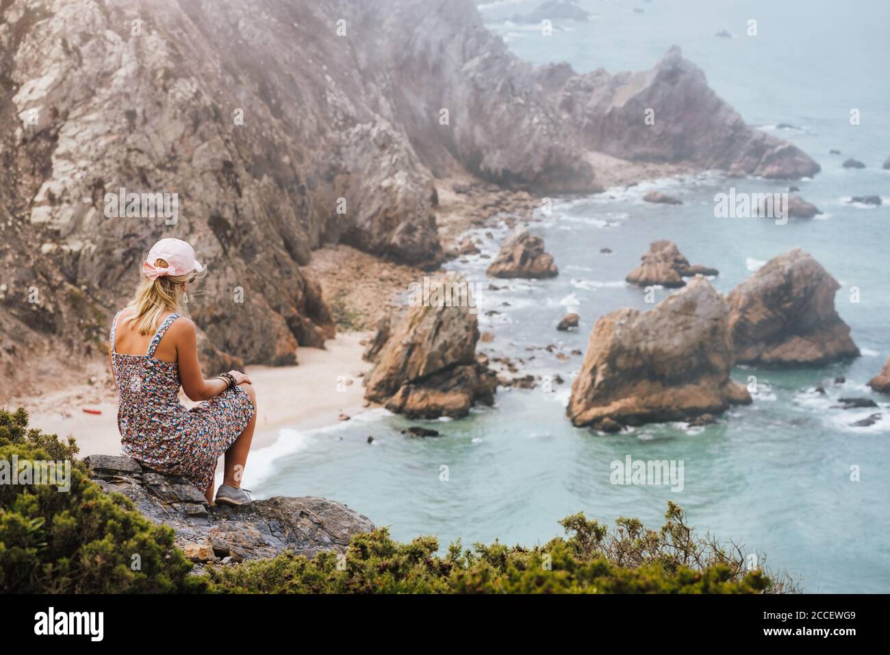 Erwachsene Frau genießt schönen Strand Praia da Ursa im Morgenlicht. Surreale Landschaft von Sintra, Portugal. Küstenlandschaft des Atlantischen Ozeans. Stockfoto
