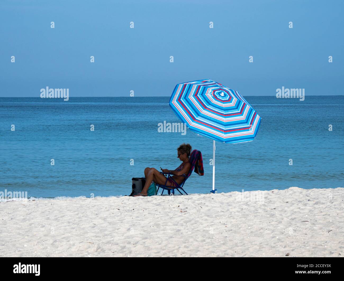 Frauen, die in der Strandliege unter einer Sonnenliege am Strand sitzen Florida in den Vereinigten Staaten Stockfoto
