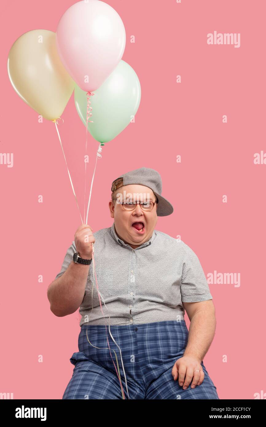 Fröhlicher lustiger emotionaler Mann in den 30er Jahren in grau gekleidet  t-Shirt in karierte Hosen eingesteckt, überglücklich und begeistert Sein  guter Witz mit Air bal Stockfotografie - Alamy