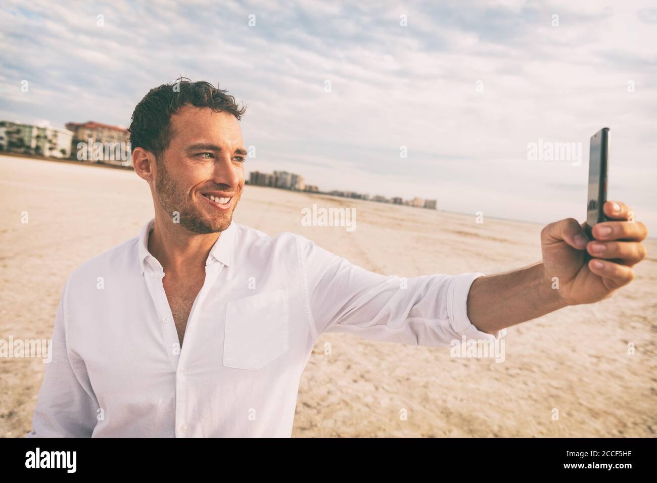 Selfie Urlaub Strandmann in weißem Leinen Shirt fotografieren mit Handy auf Hochzeitsreise Urlaub. Glückliche junge mit Smartphone auf holdiay Stockfoto