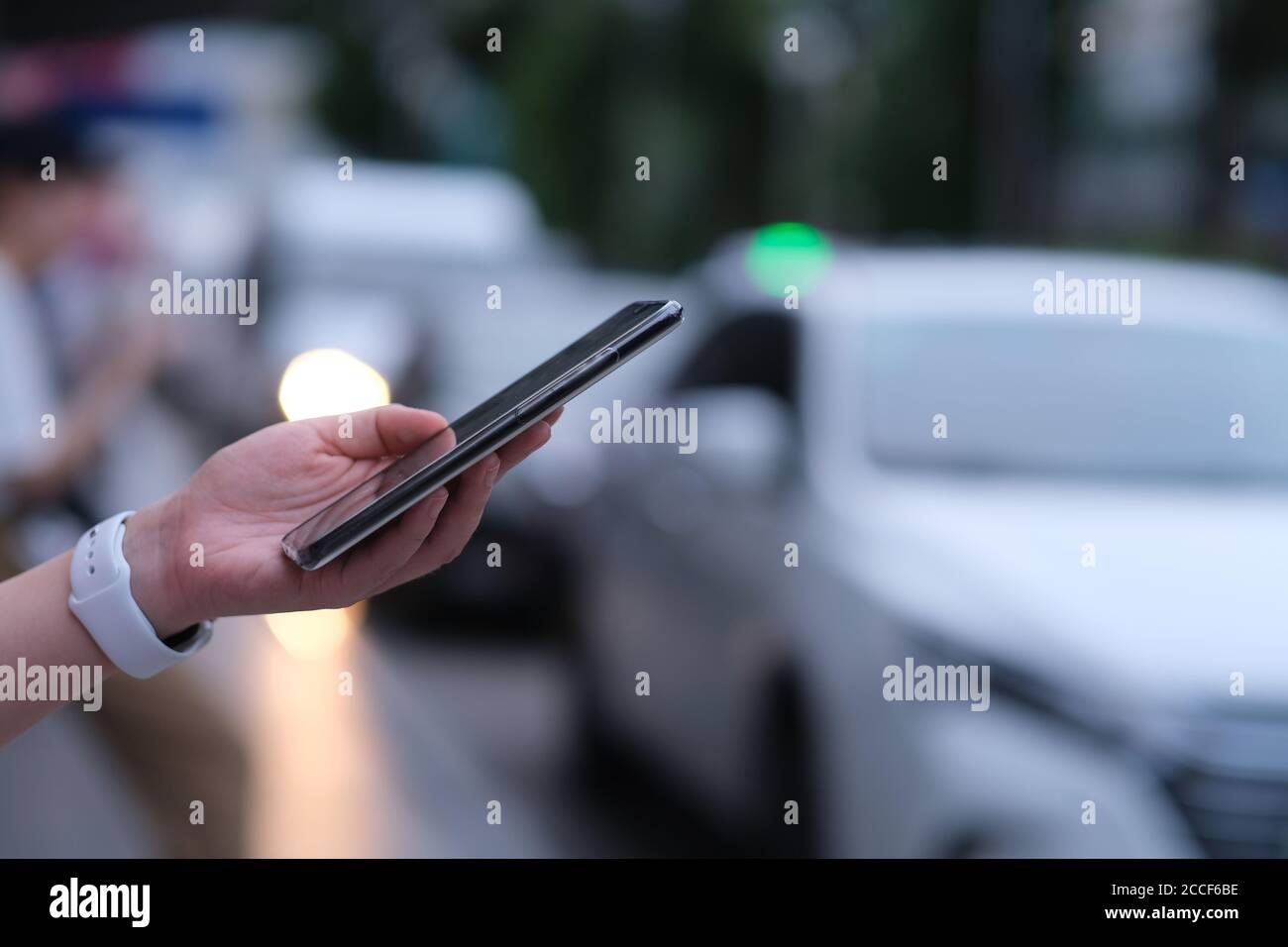 Nahaufnahme Hand mit Smartphone auf der Straße. Verschwommene Autos Hintergrund Stockfoto