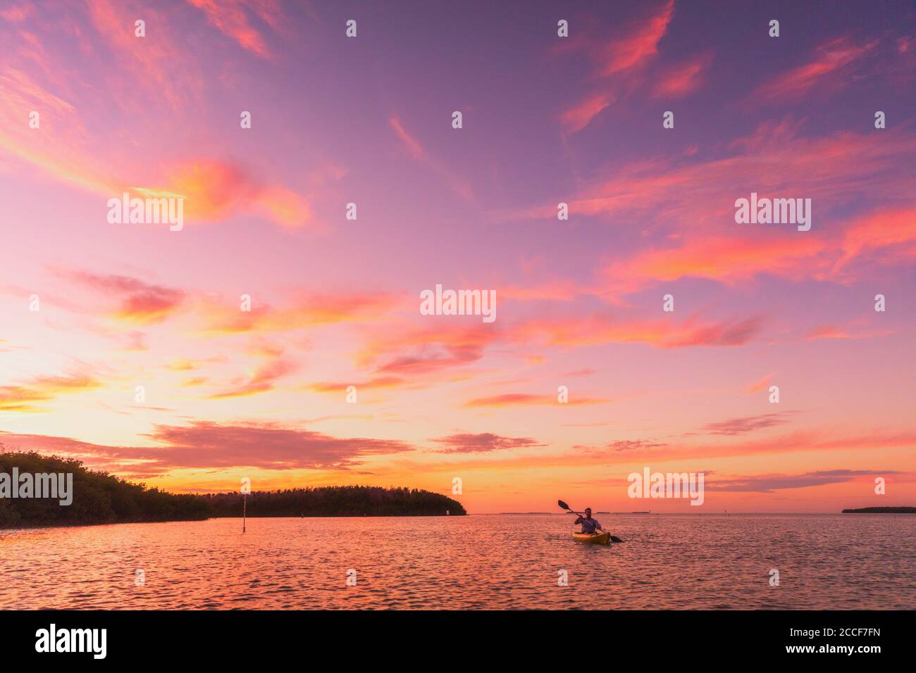 Kajakfahrer Mann Kajak Meer Kajak bei Sonnenuntergang auf Sommer Ozean Natur Landschaft. Atemberaubende Landschaft mit rosa Himmel Stockfoto