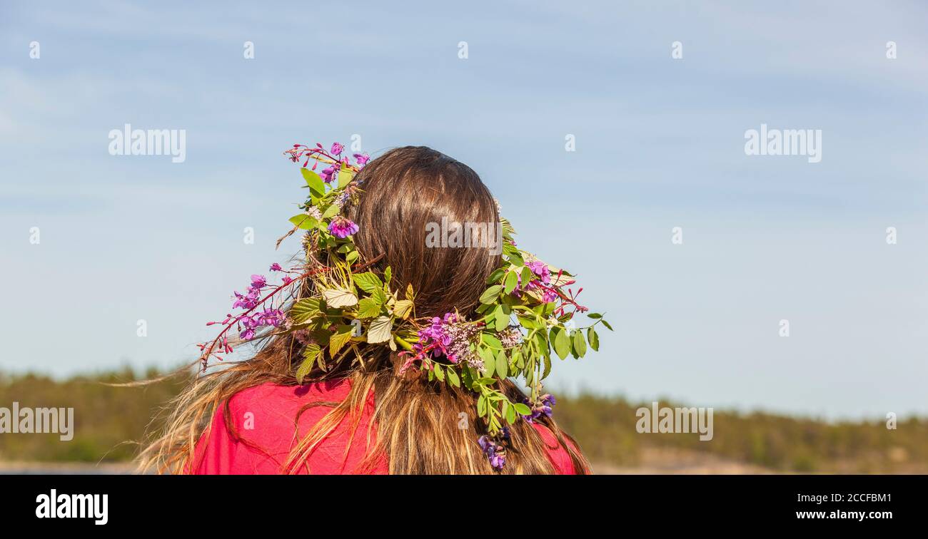 Junge Frau mit Blumenkranz im Hochsommer in Schweden Stockfoto