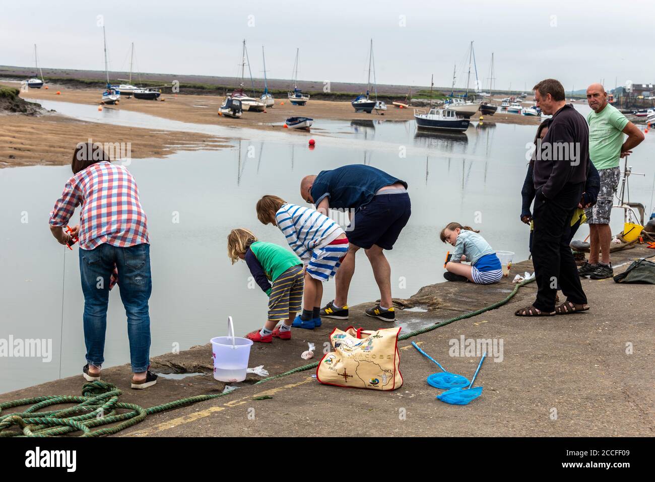 Familien, die gerne kleine Krabben an der Hafenmauer von Wells-next-the-Sea an der Nord-Norfolk-Küste fangen, Großbritannien, Stockfoto
