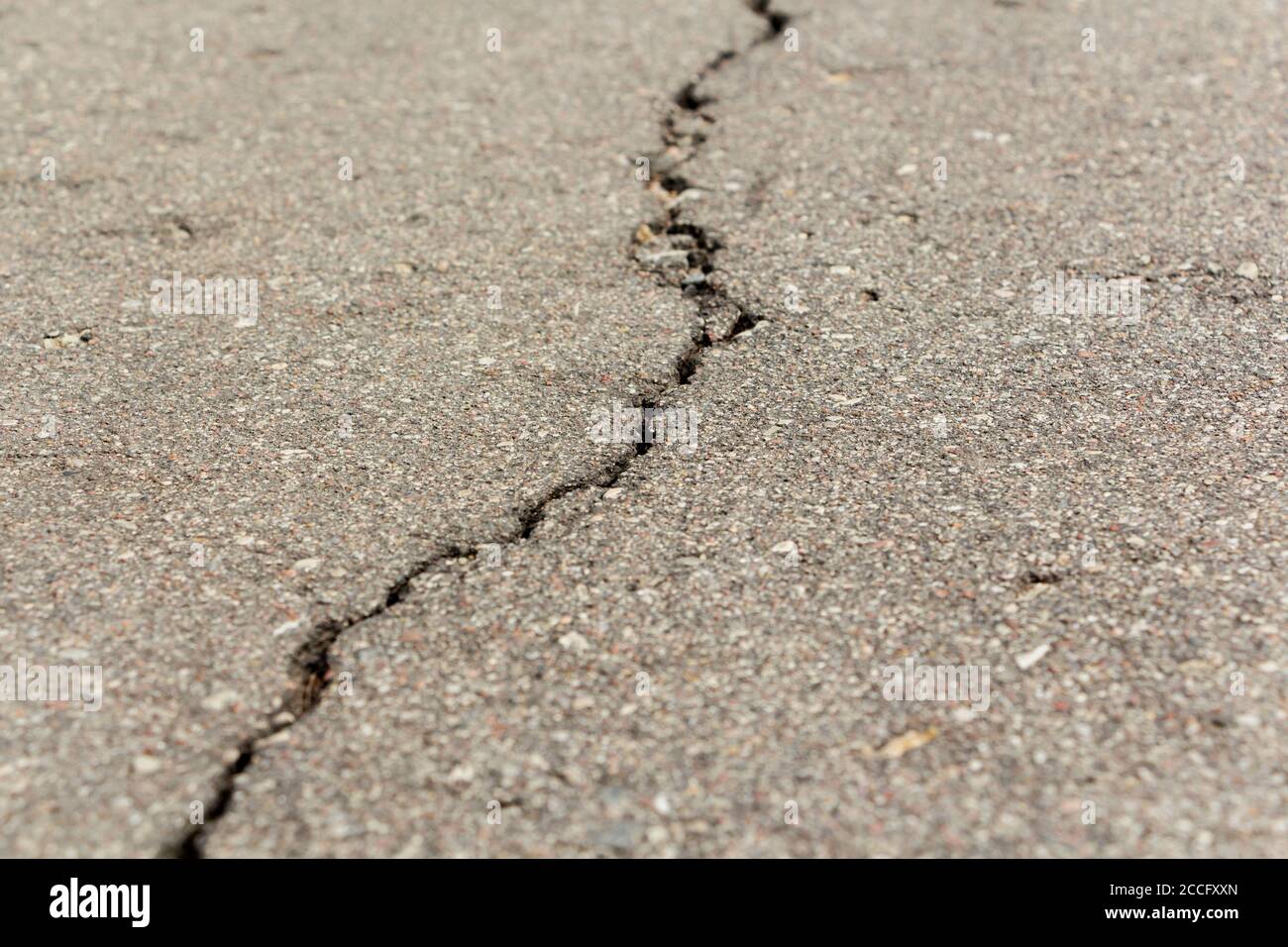 Asphalt mit über die Oberfläche abstrahlenden Rissen. Stockfoto