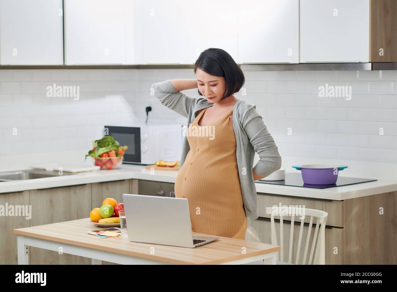 Junge schwangere Frau leidet unter Kopfschmerzen im Home Office Stockfoto