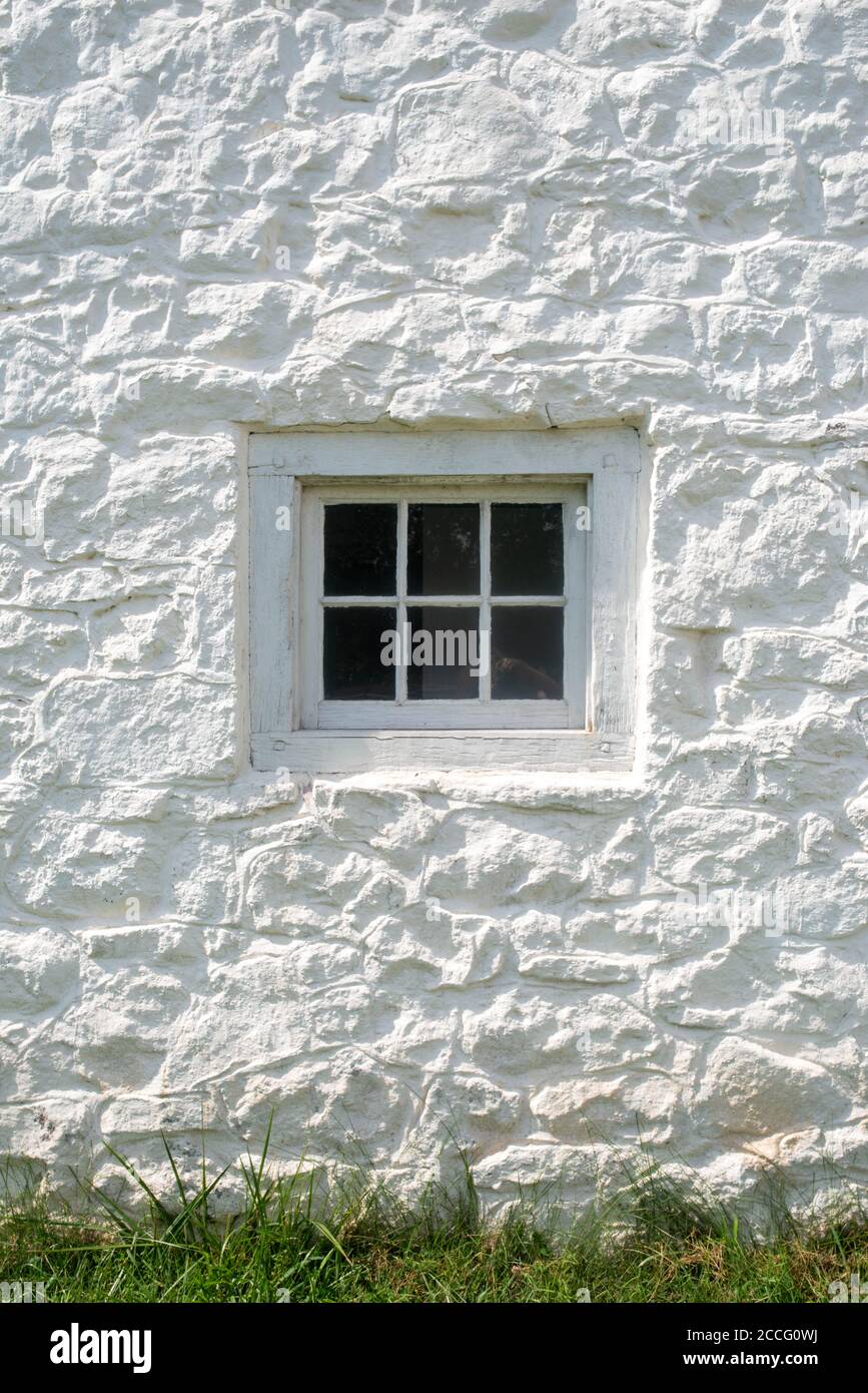 Vertikales Bild von weiß getünchten Stein schimmern in natürlichem Licht mit kolonialen antiken Glasfenster und Fensterrahmen mit Holzdübel gemacht. Stockfoto