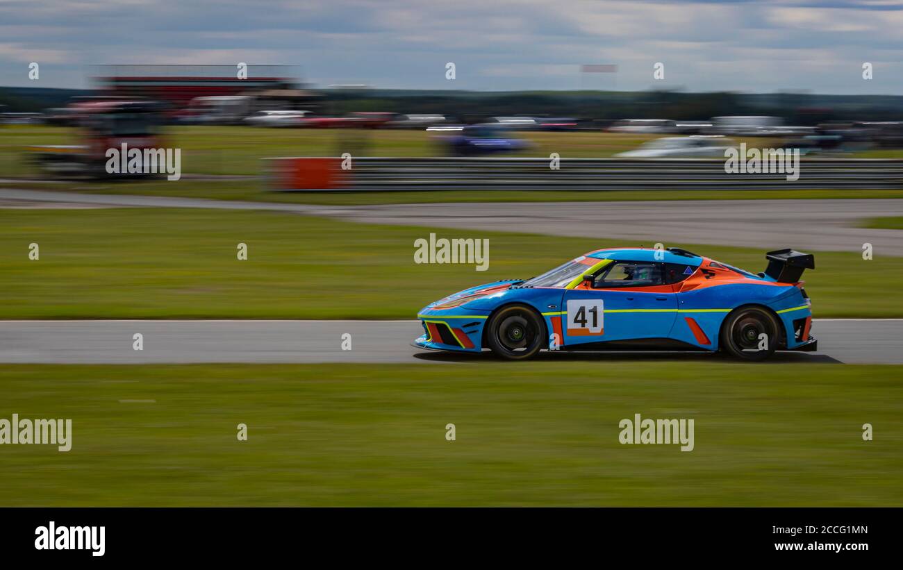 Eine Schwenkaufnahme eines blauen und orangenen Rennwagens, der eine Strecke fährt. Stockfoto