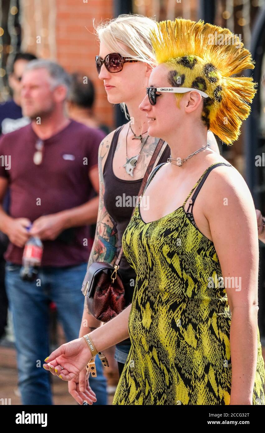 Zwei Punk-Mädchen beim Blackpool Rebellion Festival. Das Motiv ist mit einem spektakulären orange-gelben Mohican und passendem Kleid ausgestattet. Stockfoto
