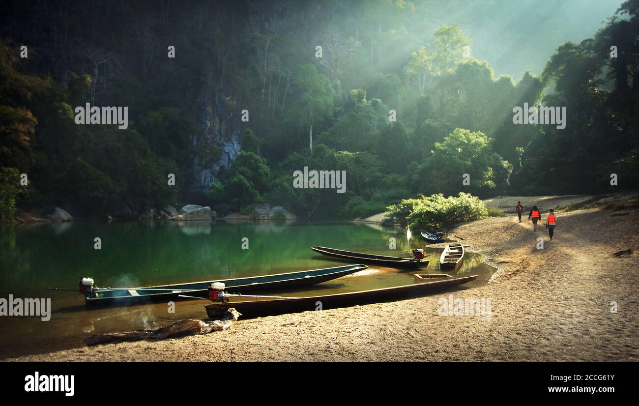 Drei Menschen gehen von ihren Booten zum Kong Lor Höhle in Laos im asiatischen Dschungel Stockfoto
