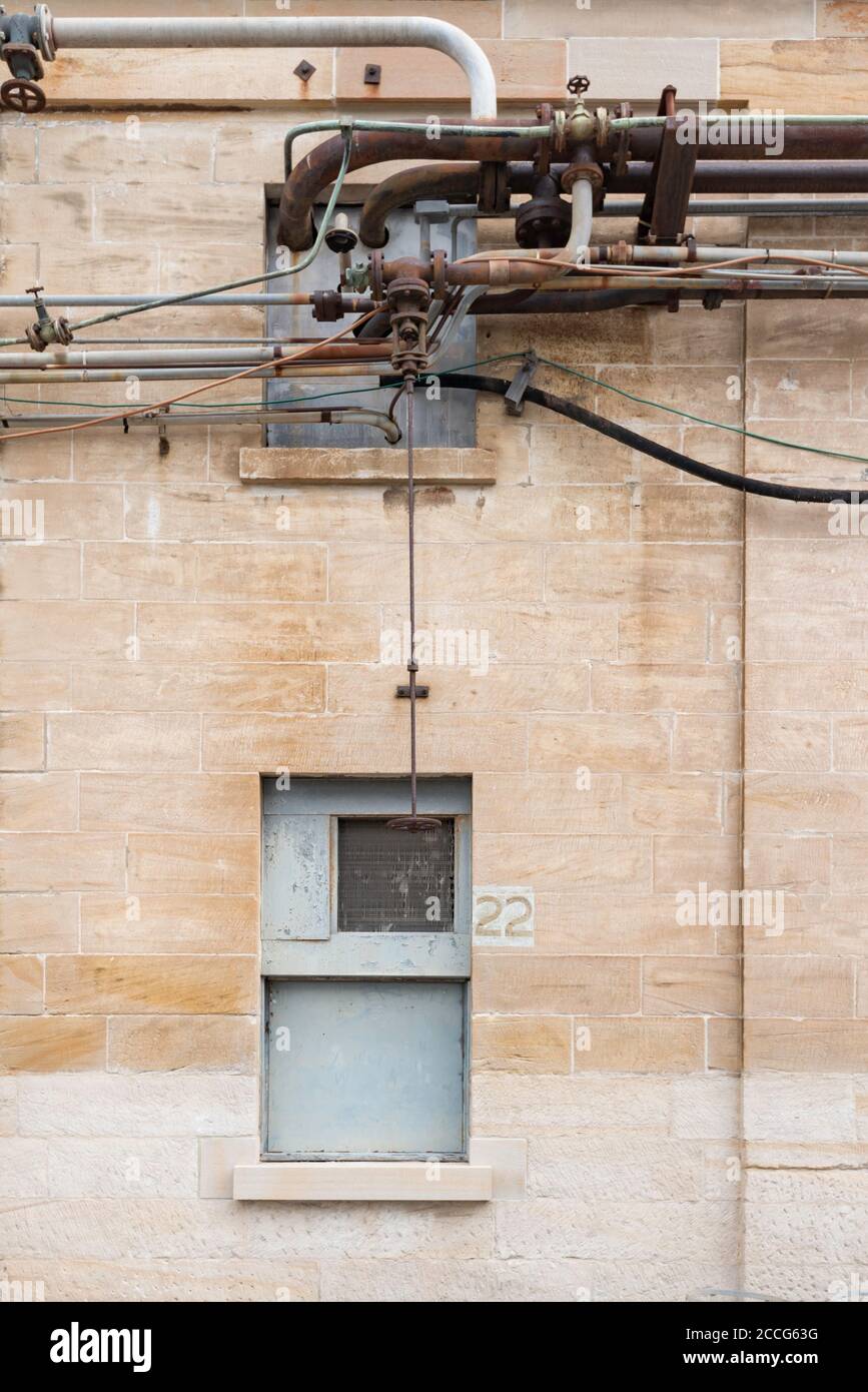 Blick auf eine komplexe Reihe von Sanitär vor einem der ehemaligen Workshops auf Cockatoo Island in Sydney Harbour, New South Wales, Australien Stockfoto