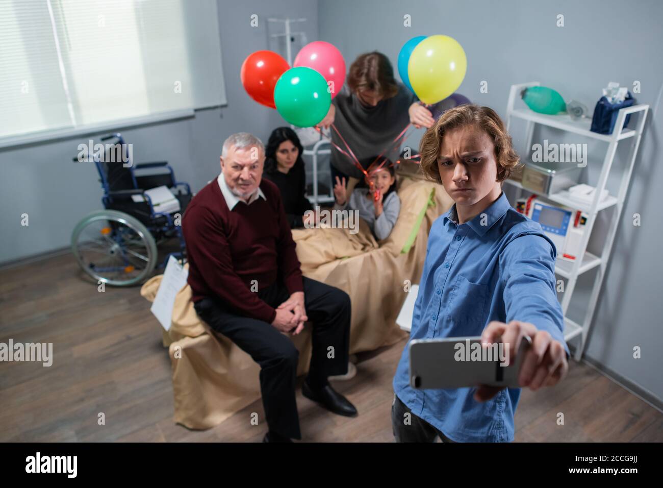 Ein Junge macht Gesichter, während er ein Selfie mit seiner kranken kleinen Schwester und der ganzen Familie macht. Stockfoto