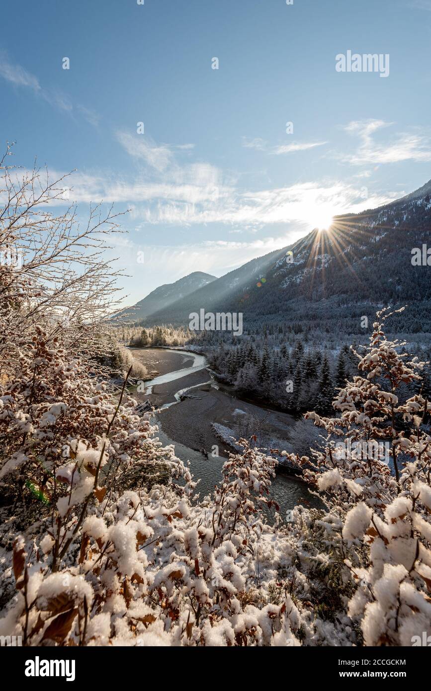 Sonne mit Sonnenstrahlen auf dem Berghang oben Die schneebedeckten Isarwiesen im Frühling Stockfoto