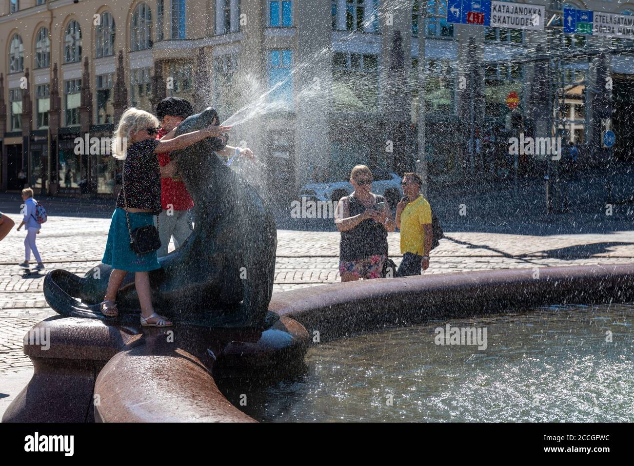 Junge Mädchen, die mit Wasserspüllenden Seelöwen spielt, Teil der Havis Amanda Skulptur oder Statue von Ville Vallgren, in Helsinki, Finnland Stockfoto