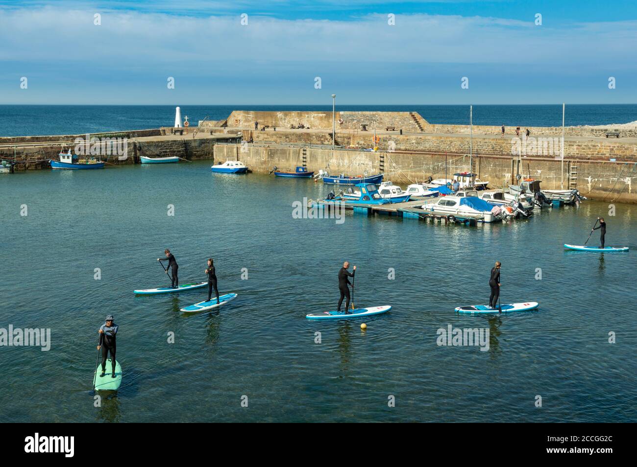 CULLEN BAY MORAY KÜSTE SCHOTTLAND HAFEN UND MENSCHEN AUF PADDEL PLATINEN Stockfoto