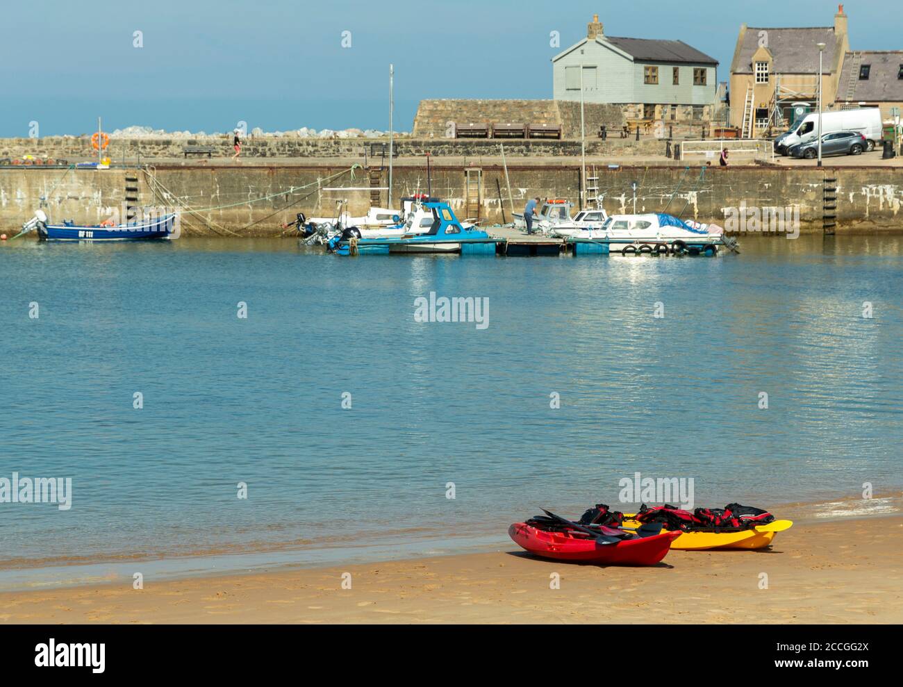 CULLEN BAY MORAY KÜSTE SCHOTTLAND HAFEN UND KLEINER SANDSTRAND MIT ROTEN UND GELBEN KAJAKS Stockfoto