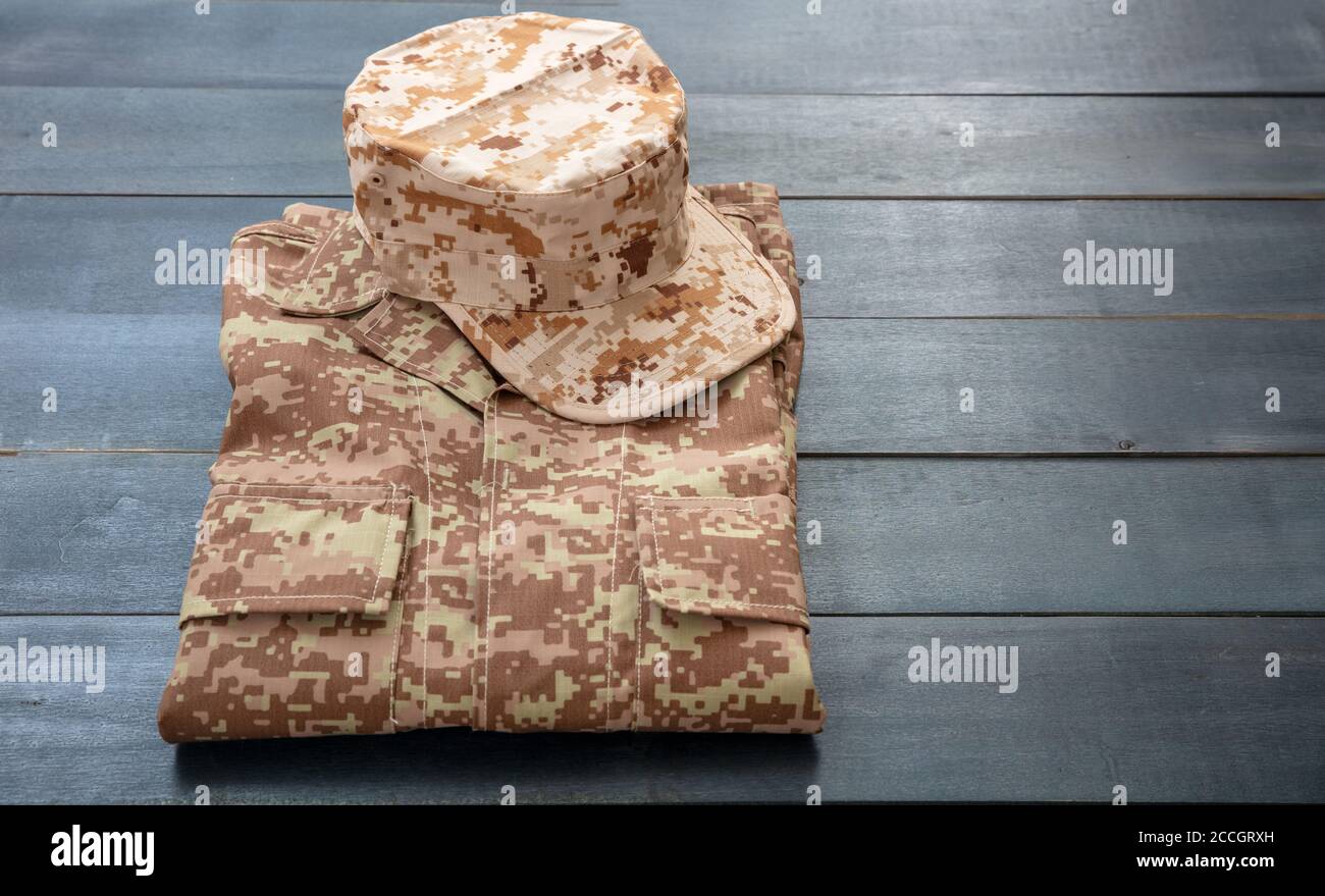 US-Armee-Mütze auf einem gefalteten Uniform, blaue Farbe Holzhintergrund. Militär Camouflage digitale Wüste Muster Shirt und Kopfbedeckung Stockfoto