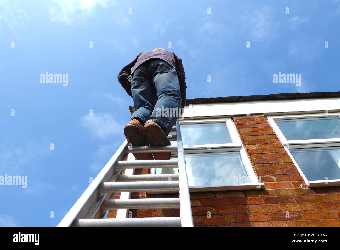 Mann auf Leiter gegen Hauswand und Fenster, an denen gearbeitet wird  Faszienbrett mit tiefblauem Himmel Stockfotografie - Alamy