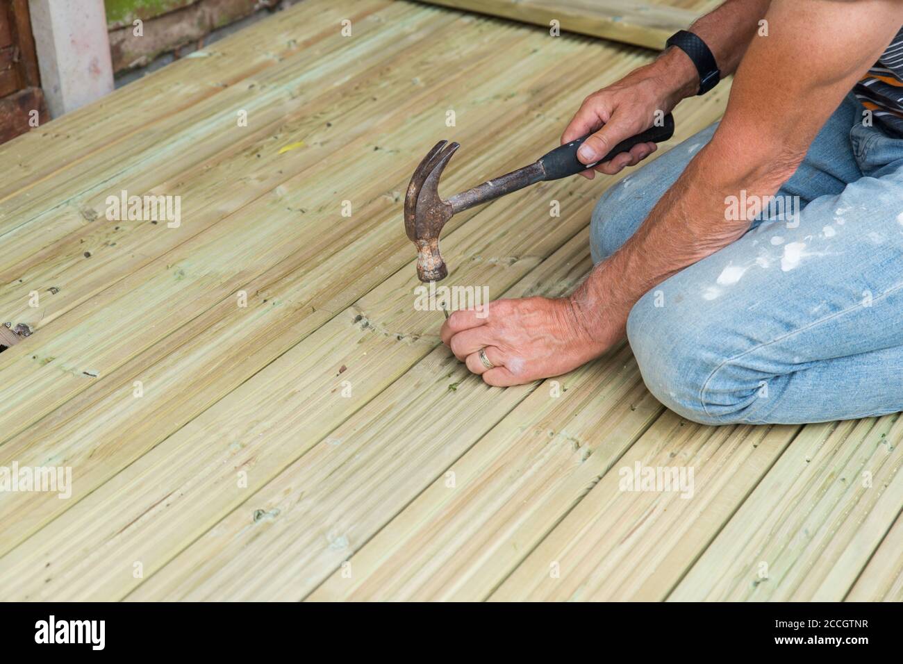 Nahaufnahme von Menschenhänden Hämmern einen Nagel zu machen Holzterrasse zu Hause für den Garten während des Schließens Stockfoto