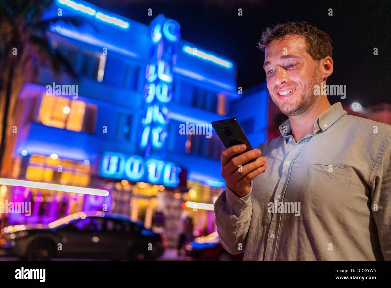 Miami Mann SMS Telefon zu Fuß auf Ocean Drive South Beach Florida. Art Deco Hotels und Restaurants in der Nacht weltbekannten Touristenziel für Stockfoto