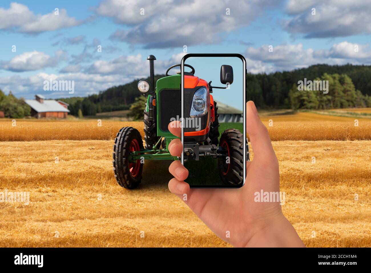 Alter Traktor auf dem Bauernhof. Der Landwirt zeigt sein Telefon darauf und ein neuer moderner Traktor wird auf dem Bildschirm angezeigt. Stockfoto