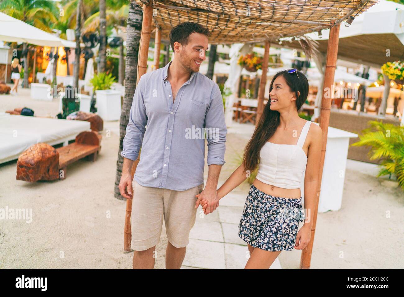 Sommerurlaub glückliches Paar im Tropical Beach Resort Hotel, das zum Strand läuft. Junge interracial Menschen halten Hände in lässigen Kleidung. Karibik Stockfoto