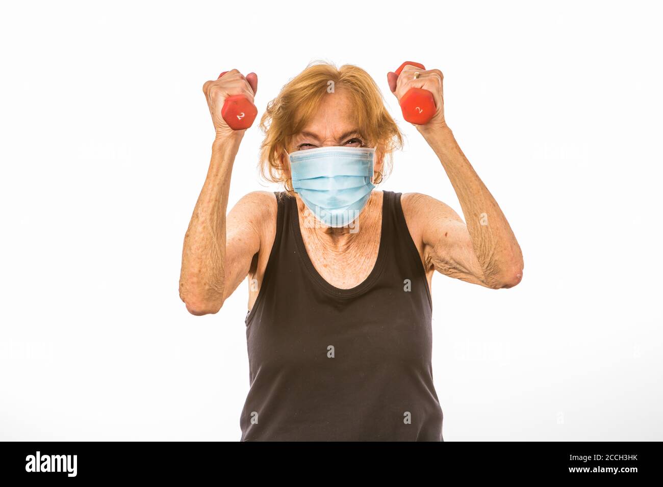 Senior Woman Defiant Über Das Heben Von Zwei Pfund Gewichte Während Des Tragens Eine Gesichtsschutzmaske Stockfoto