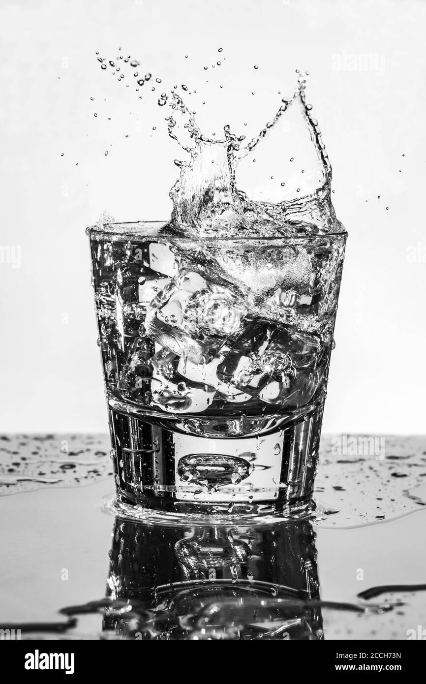 Eiswürfel spritzt in ein Glas Wasser - selektiver Fokus. High-Speed-Fotografie Stockfoto