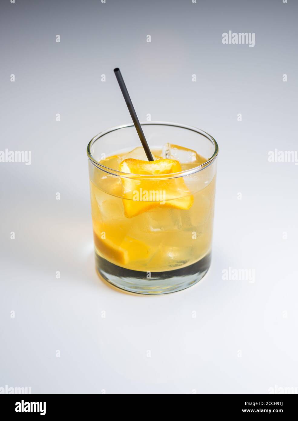 Ein Craft Cocktail mit Stroh und Orange garnieren auf einem Weißer Hintergrund Stockfoto