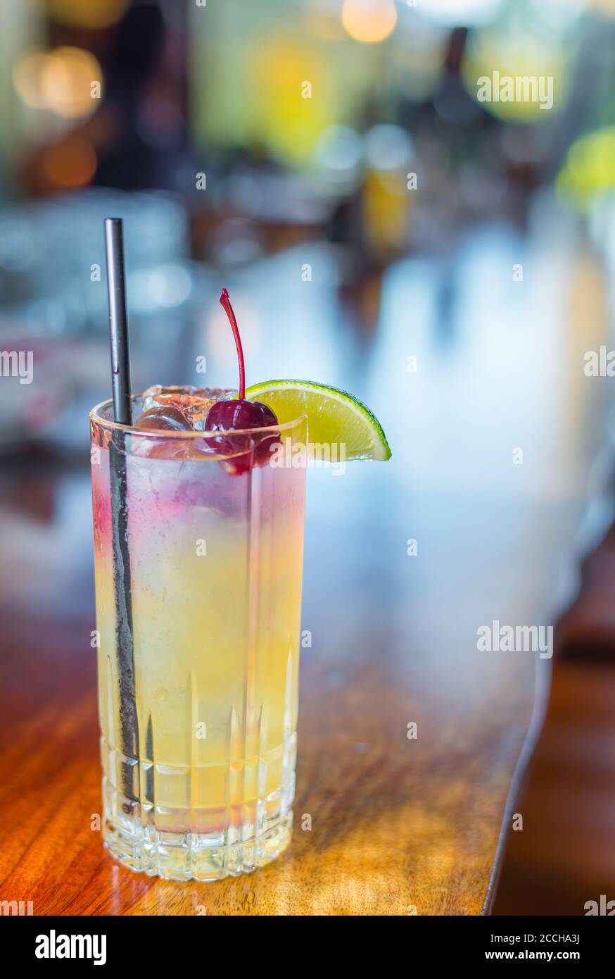 Ein erfrischender und süßer tropischer Craft-Cocktail in einem collins Glas mit Limette & Kirsche garnieren in einem lebendigen gezeigt Bar- oder Restaurantumgebung Stockfoto