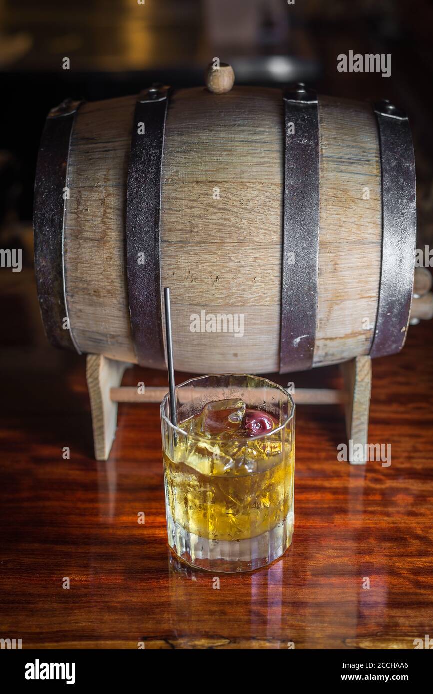 Eine rustikale Barszene mit einem klassischen Craft-Cocktail aus Bourbon-Whiskey und einem Fass auf der Holzbar. Stockfoto