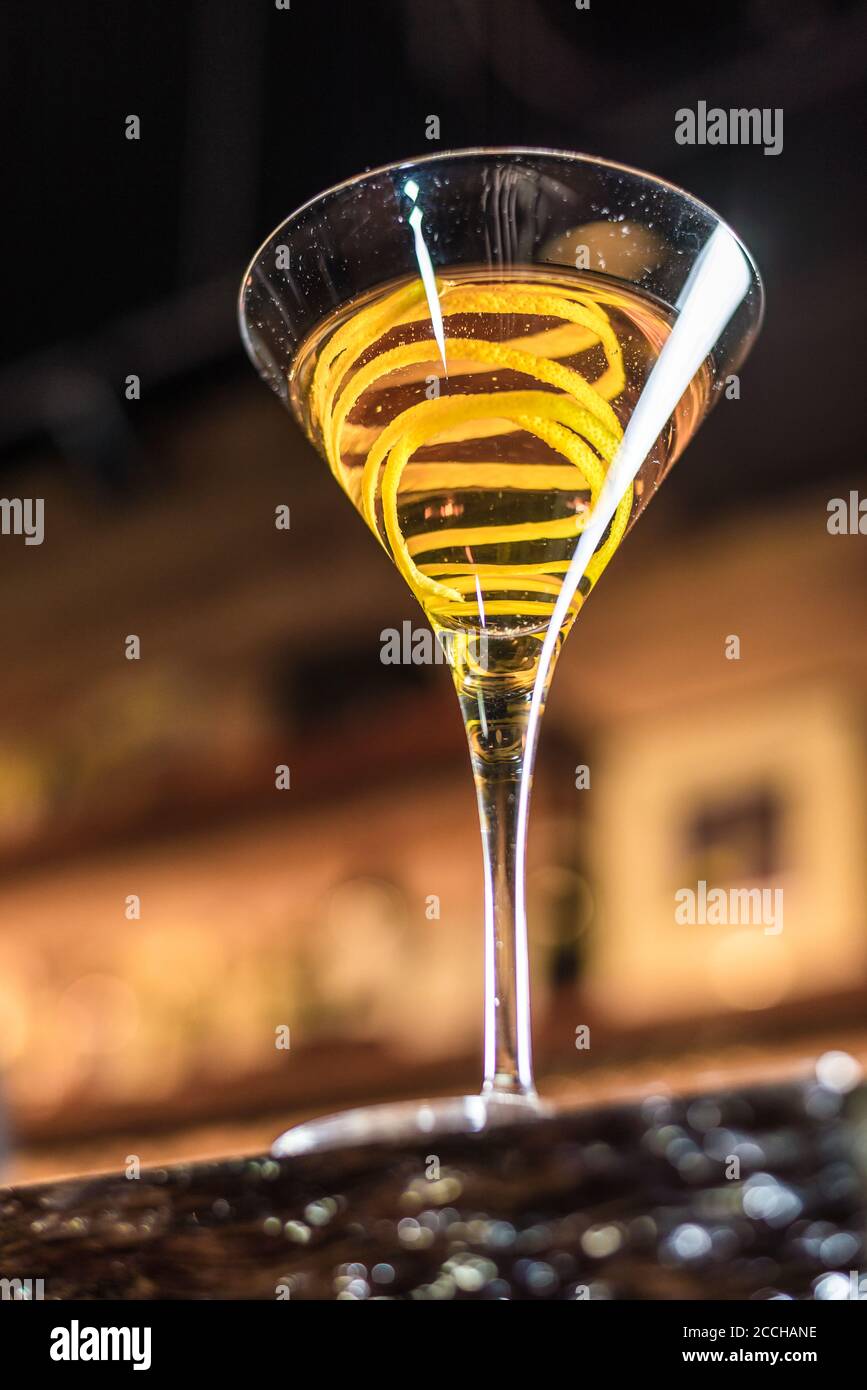 Blick auf einen Craft-Cocktail in einem martini-Glas Mit einer Zitronenschale garnieren ist eine Bar Einstellung Stockfoto