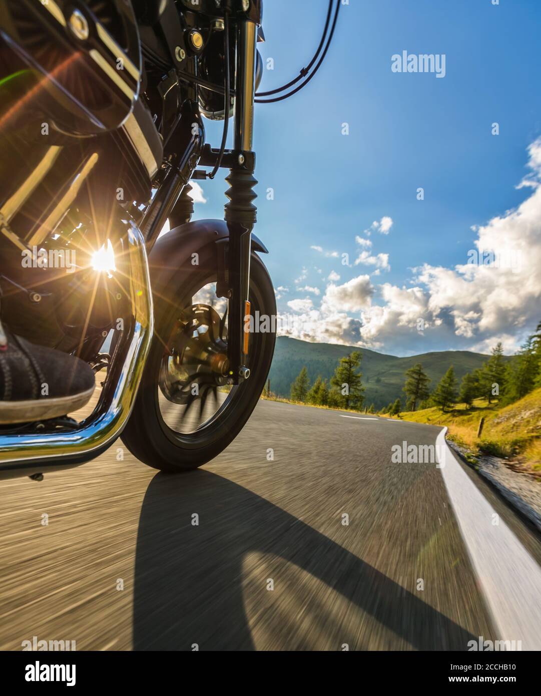 Detail der Motorrad Vorderrad. Blick vom Beifahrer Perspektive, wunderschönen alpinen Landschaft im Abendlicht. Reisen und Sport Fotografie im Freien Stockfoto