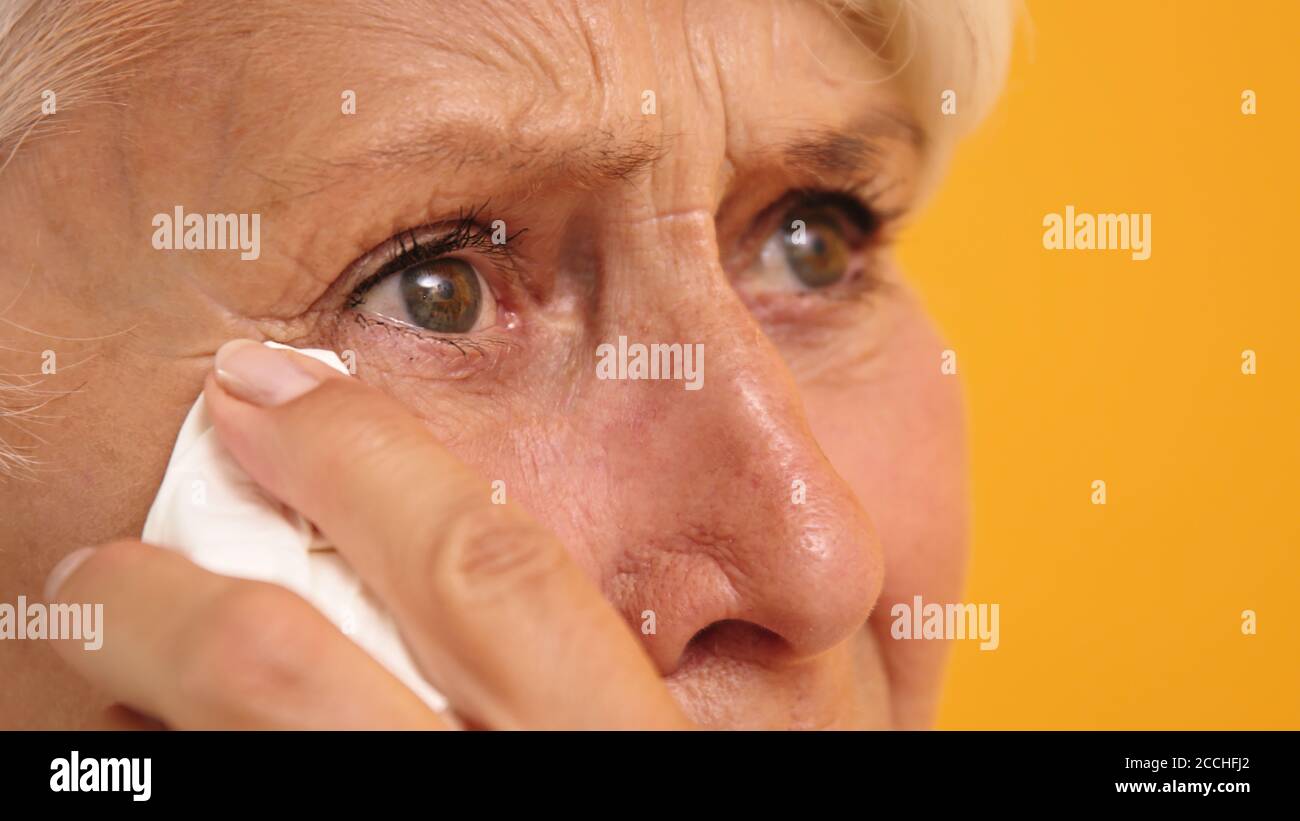 Nahaufnahme der traurigen verwundbaren alten Frau, die ihre Tränen wischte. Hochwertige Fotos Stockfoto