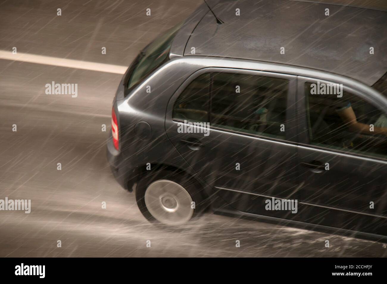 Verschwommenes Auto auf der Straße vom starken Regen mit Hagel getroffen, an einem regnerischen Tag in Bewegung verschwommen Schwenken von oben geschossen Stockfoto