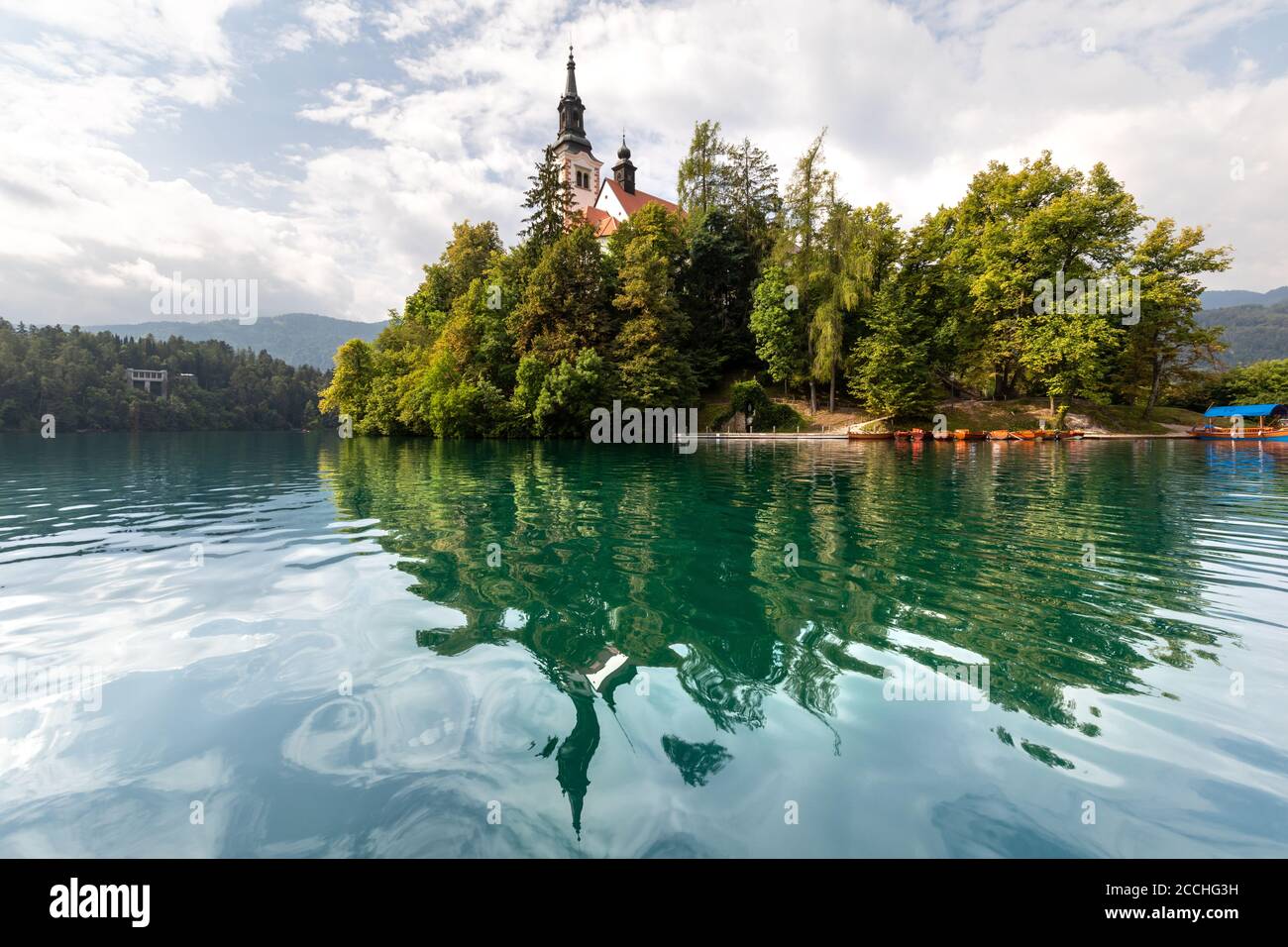Die kleine Insel in der Mitte des slowenischen Sees von Bled, umgeben von Vegetation, reflektiert auf dem Wasser Stockfoto