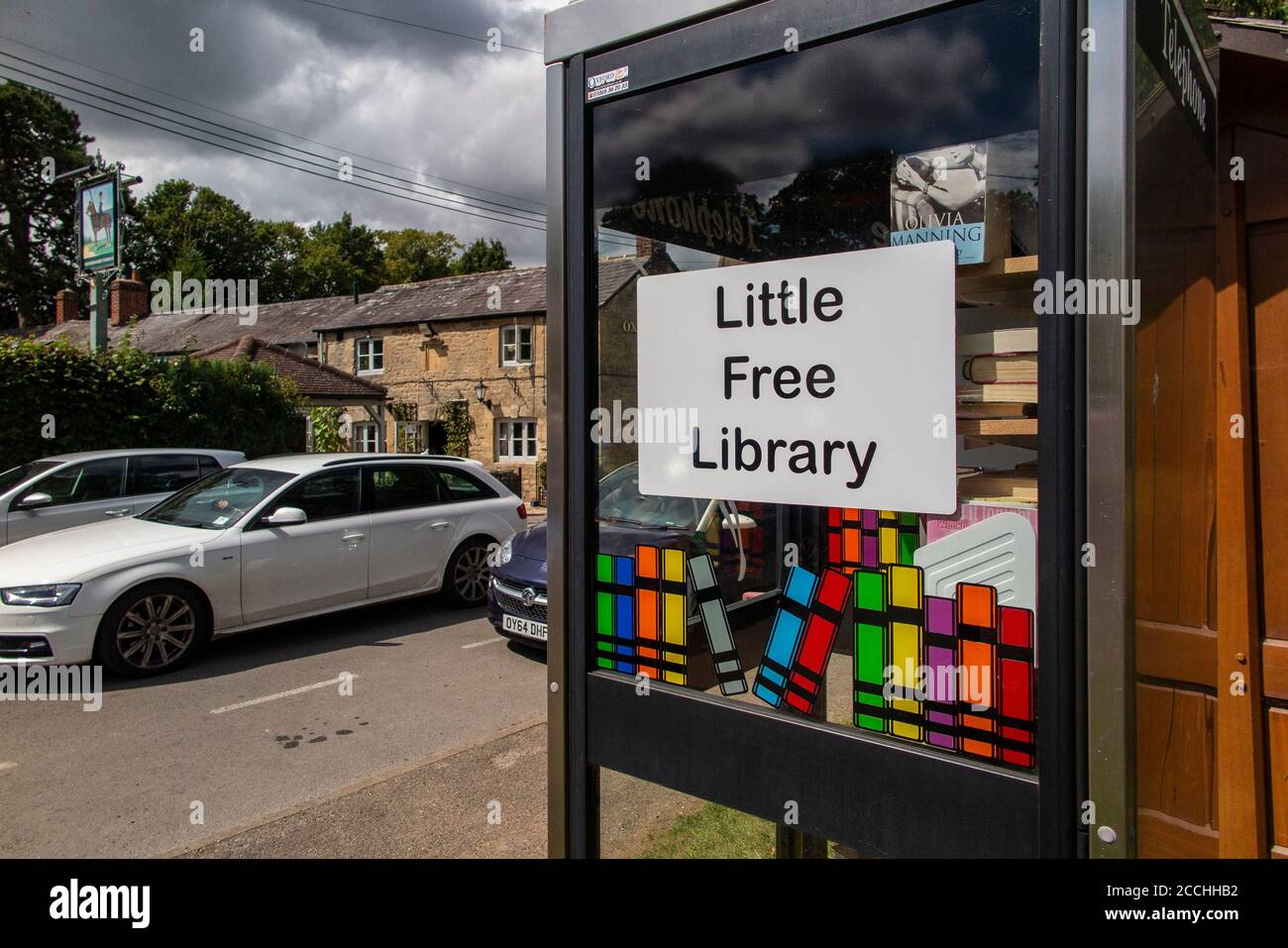 Eine kleine, kostenlose Bibliothek in einem Dorf in Oxfordshire, die eine alte Telefonbox umgab Stockfoto