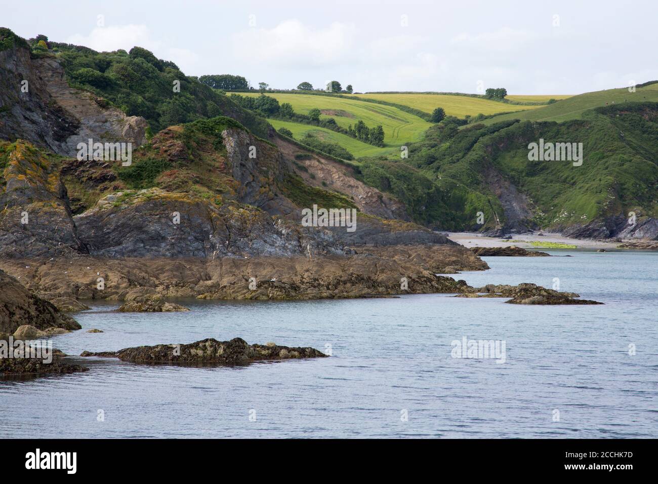 Blick auf felsige Küste und Hügel hinter geschützter Bucht und Strand, Mevagissey, Cornwall, Großbritannien Stockfoto