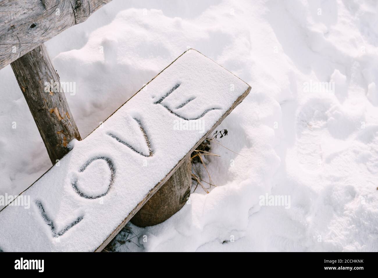 Der Schriftzug LOVE im Schnee, auf einer Holzbank. Stockfoto