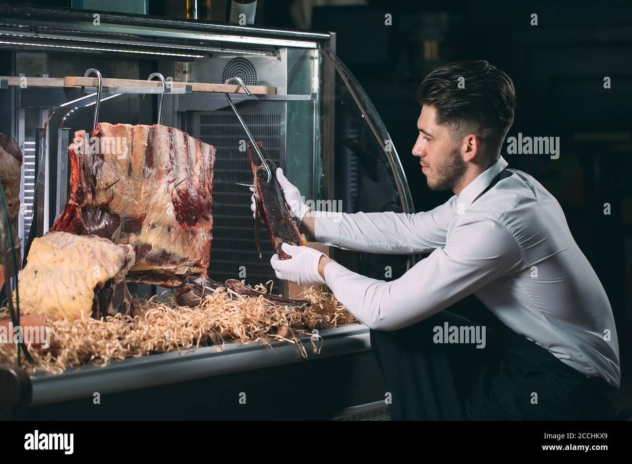 Der Kellner oder Koch bekommt trockenes Fleisch im Kühlschrank. Stockfoto