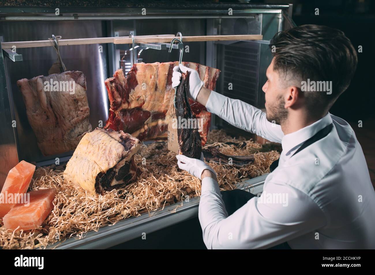 Der Kellner oder Koch bekommt trockenes Fleisch im Kühlschrank. Stockfoto