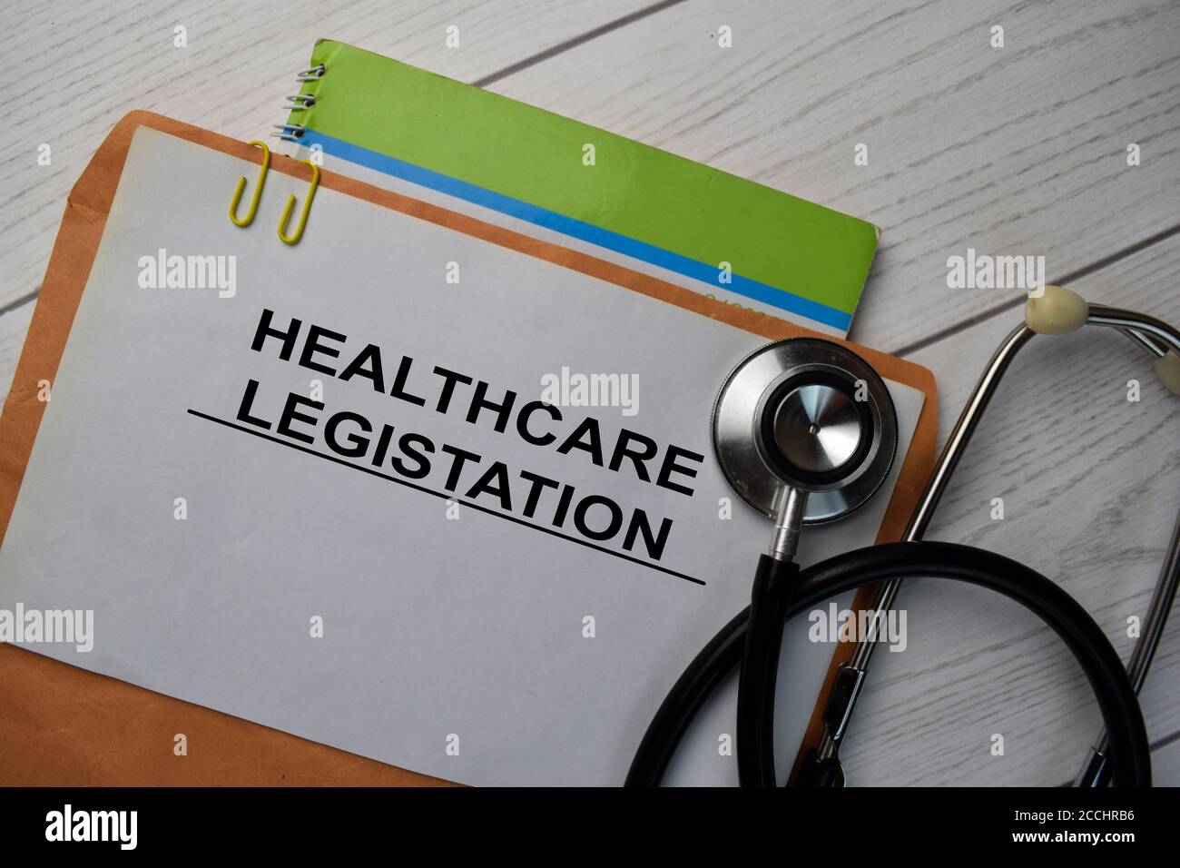 Healthcare Legistation Text mit Dokument braun Umschlag und Stethoskop isoliert auf Schreibtisch. Stockfoto