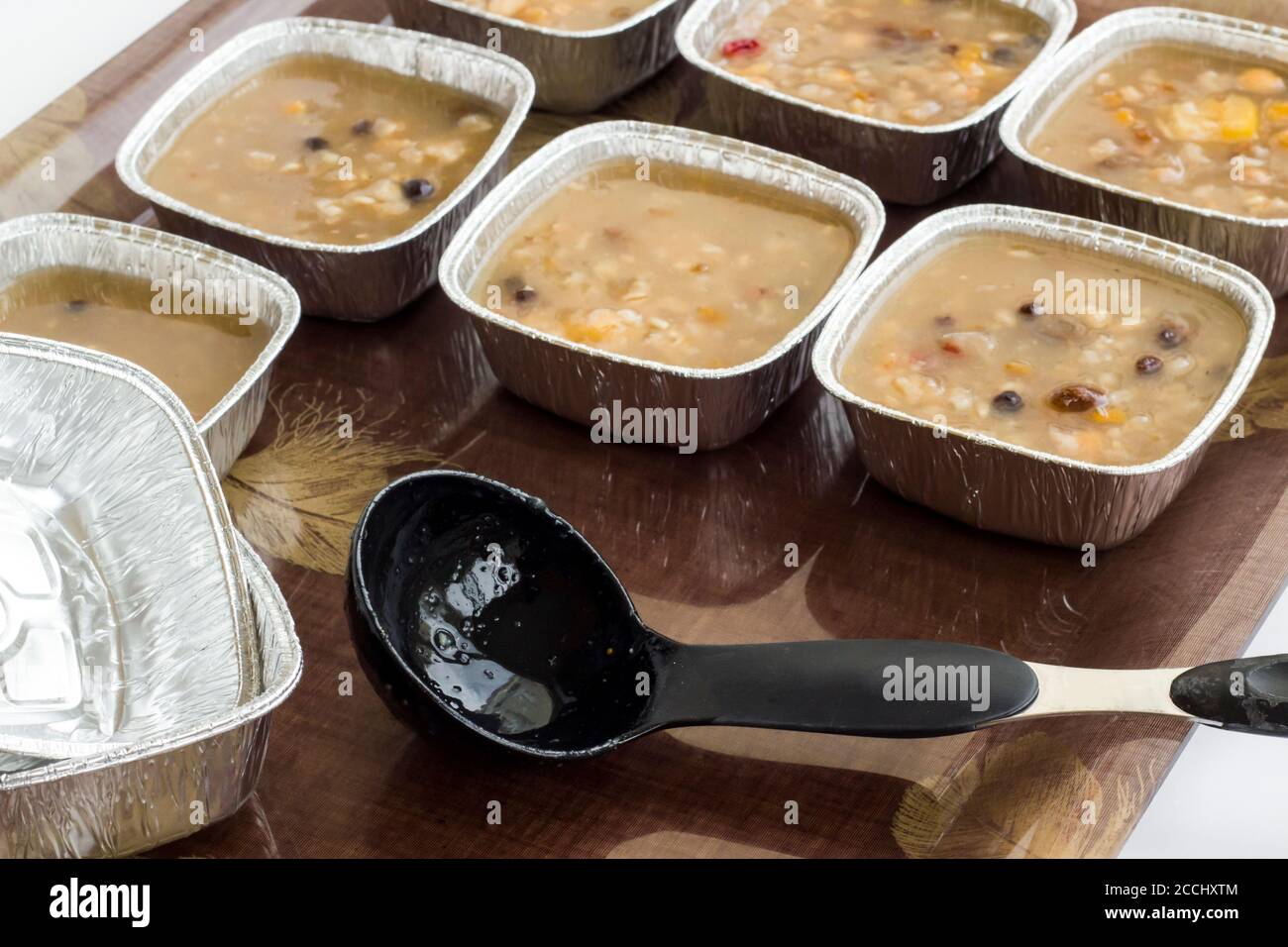 Traditionelles türkisches Dessert Asure auf Tablett mit Schöpfkelle und Aluminiumschüsseln, Folienbehälter.Essen mitnehmen. Stockfoto