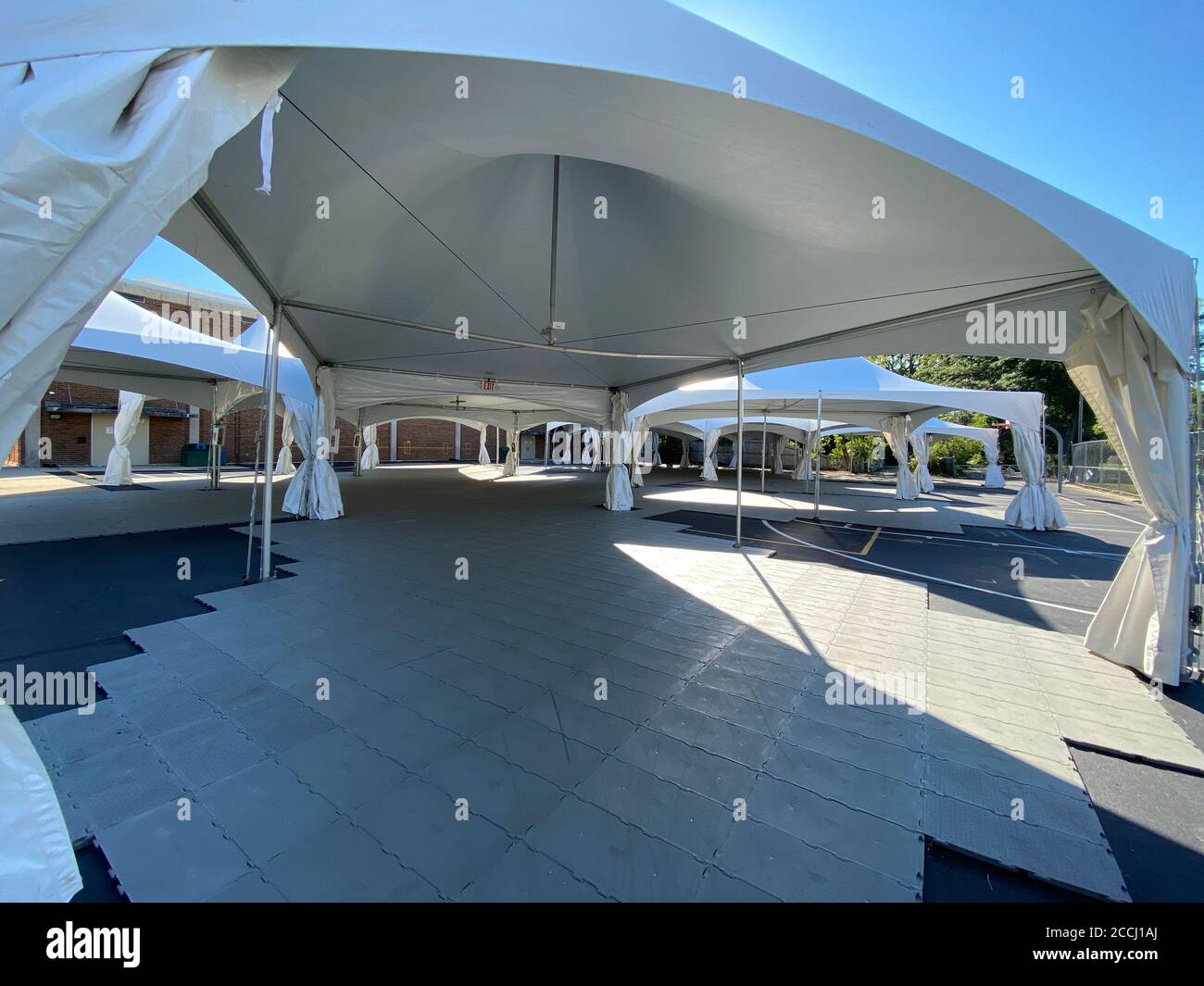 Schulen bereiten sich auf das persönliche Lernen vor, indem sie während der Coronavirus-Pandemie Zelte auf der Blacktop für Klassenräume im Freien errichten. Stockfoto