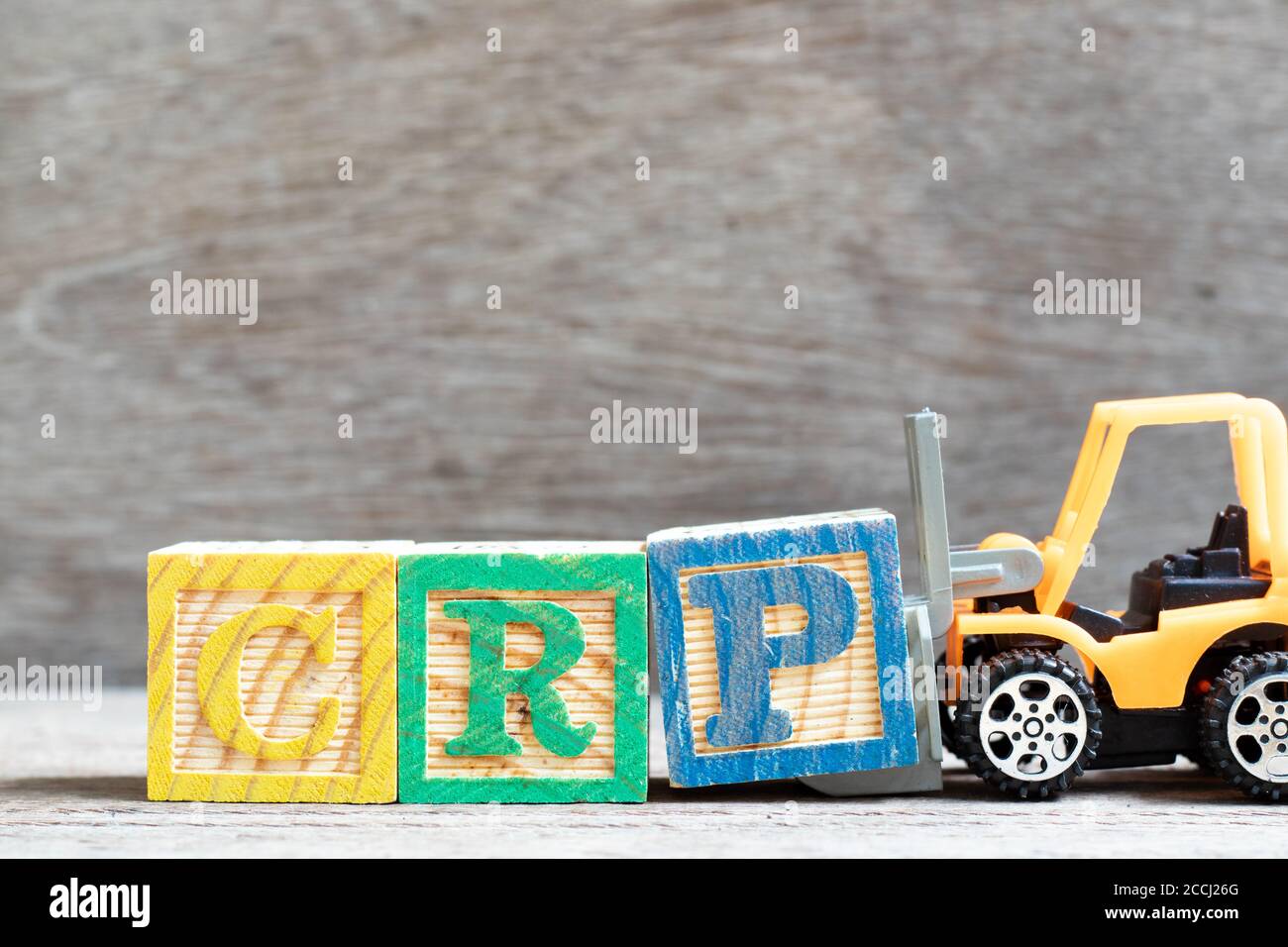 Der Gabelstapler von Toy hält den Buchstaben Block P fest, um das Wort CRP (Abkürzung des C-reaktiven Proteintests) auf Holzhintergrund zu vervollständigen Stockfoto