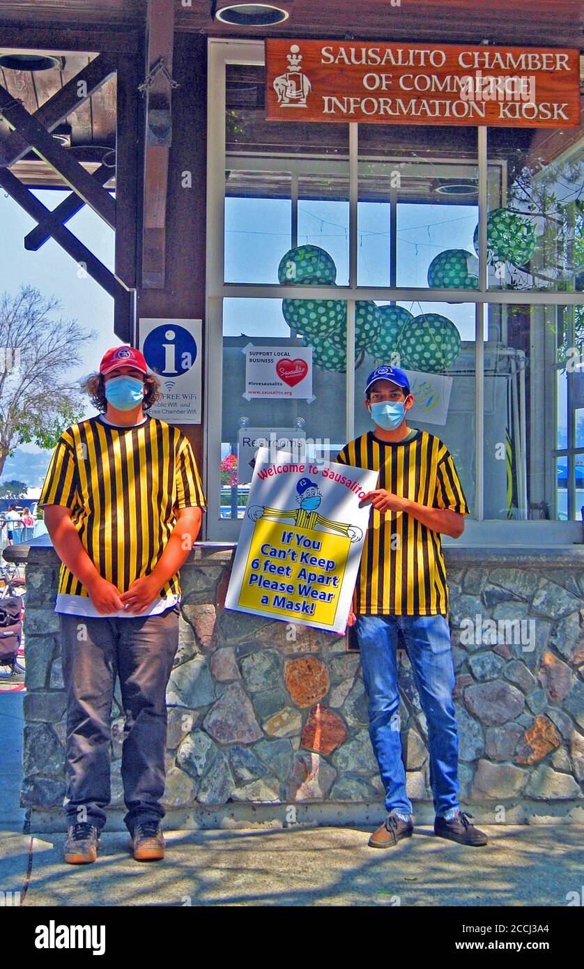 Junge Freiwillige zeigen in sausalito Schilder, die Touristen zum Tragen anraten Masken, wenn sie 6 Fuß auseinander im Freien bleiben können Stockfoto