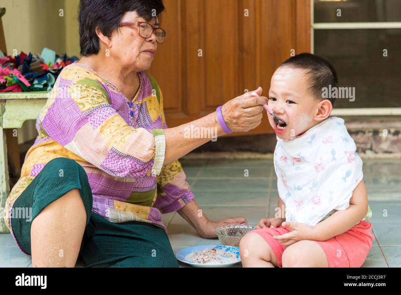 Großmutter füttert Nahrung zu thailändischem Jungen Stockfoto