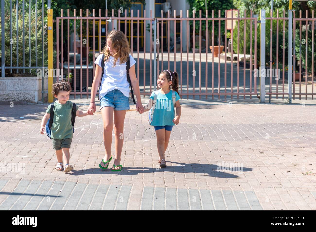 Fröhliche, vielfältige Schulkinder, die nach der Schule an sonnigen Tagen nach Hause gehen. Weichfokus. Stockfoto