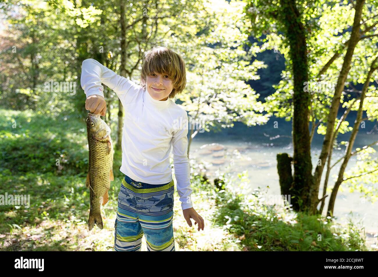 Stolzer Junge mit Fisch im Fluss gefangen Stockfoto